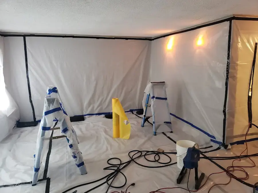 Plastic containment walls and floor protection set up in a room before work begins