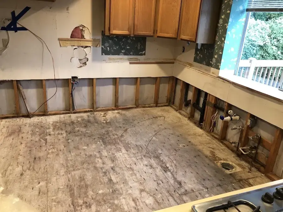 Kitchen with the lower cabinets removed and the drywall cut back above the subfloor