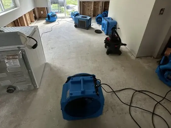 Air movers drying a room with lower drywall cut away, Arlington water damage example