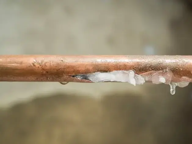 Copper pipe split open along its length with ice packed in the crack
